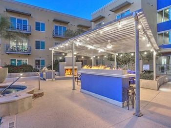 A bar with a fire pit in front of an apartment building